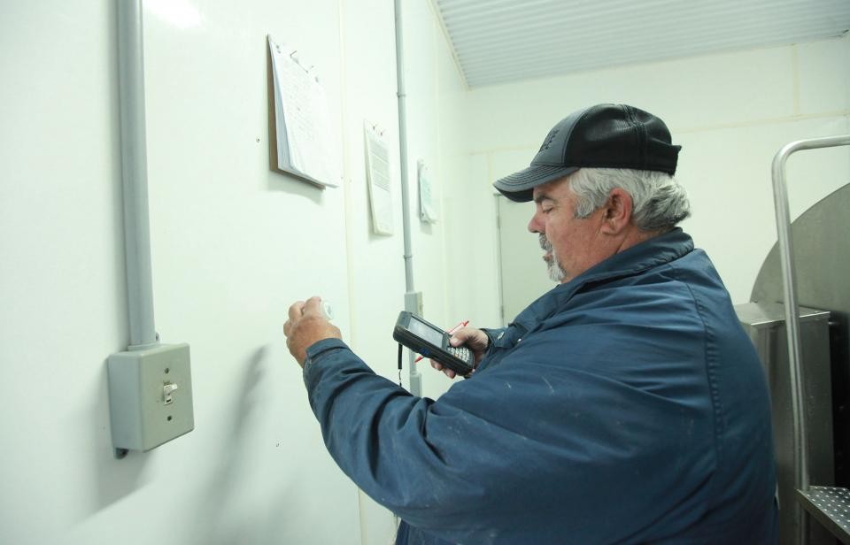 A milk truck driver and grader takes milk samples