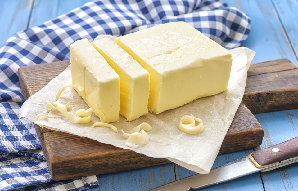 Sliced butter on wooden board placed on a blue and white checkered tablecloth 