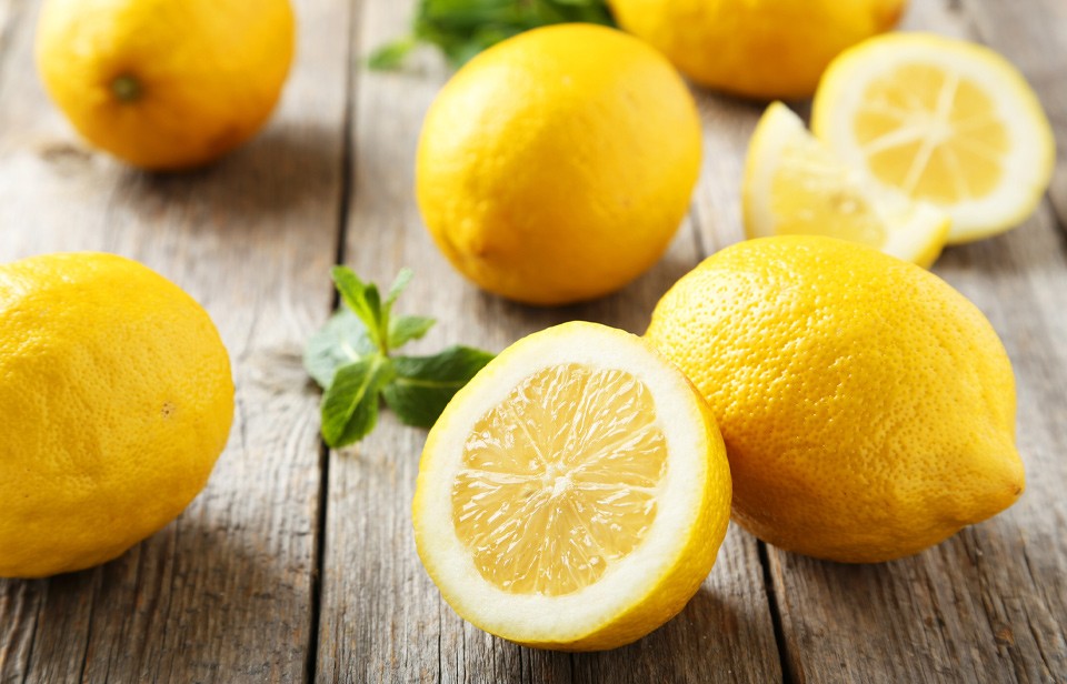 Whole and halved lemons on wooden surface. 